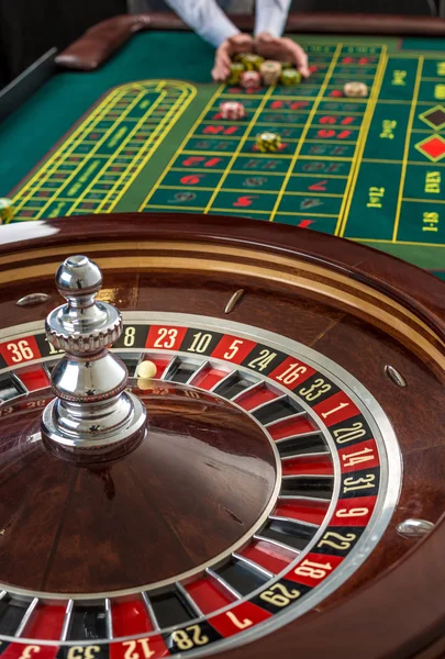 Roulette und stapelweise Spielchips auf einem grünen Tisch. — Stockfoto