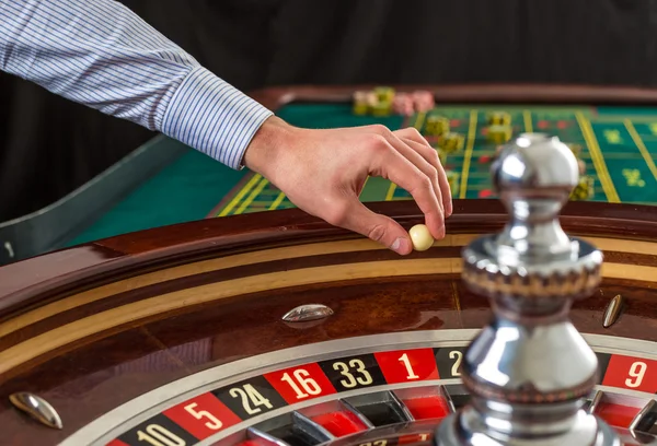 Rueda de ruleta y mano croupier con bola blanca en casino — Foto de Stock