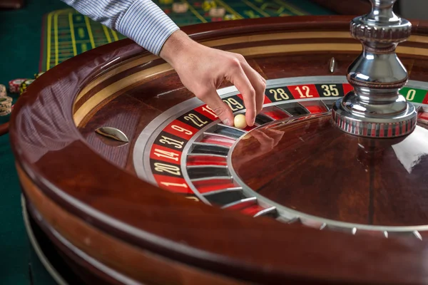 Rueda de ruleta y mano croupier con bola blanca en casino —  Fotos de Stock