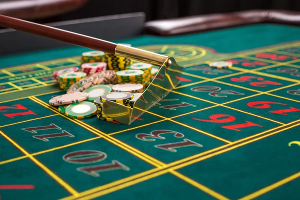 Крупним планом гральні фішки на зеленому столі в казино . — стокове фото