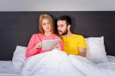 Young Sweet Couple at Bed Watching Something on Tablet Gadget