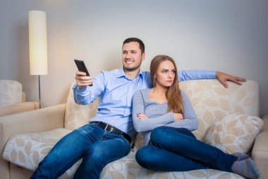 Portrait of couple sitting on sofa watching television.