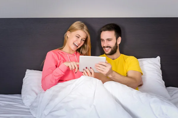 Joven dulce pareja en la cama viendo algo en la tableta Gadget — Foto de Stock