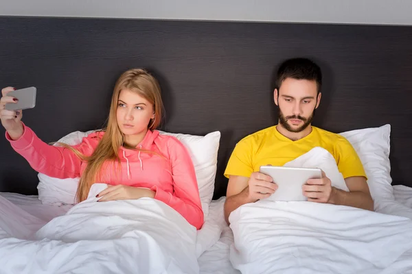 Joven feliz pareja en la cama haciendo selfie con cámara de teléfono . — Foto de Stock