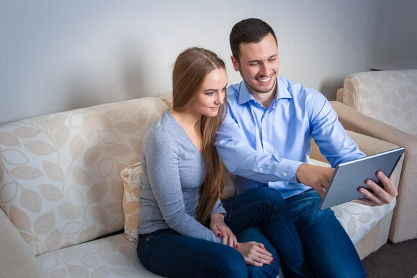 Joven hombre y mujer en el sofá con tableta electrónica — Foto de Stock