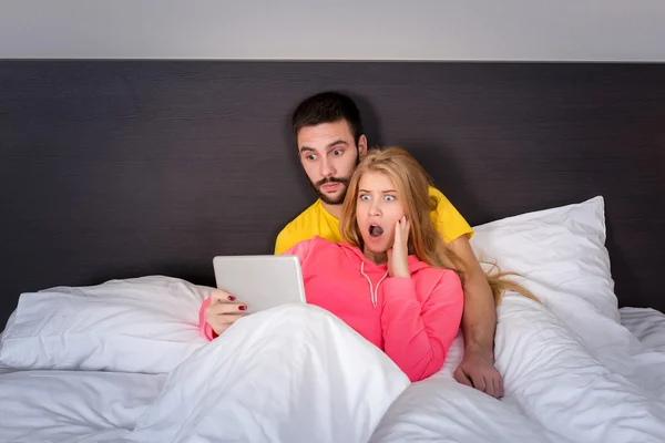 Joven dulce pareja en la cama viendo algo en la tableta Gadget — Foto de Stock