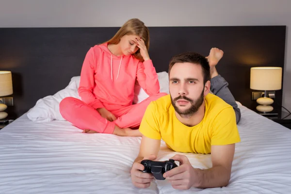 Pareja joven jugando videojuegos en la cama —  Fotos de Stock