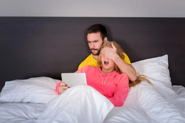 Joven dulce pareja en la cama viendo algo en la tableta Gadget — Foto de Stock