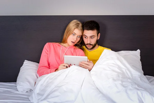 Joven dulce pareja en la cama viendo algo en la tableta Gadget — Foto de Stock