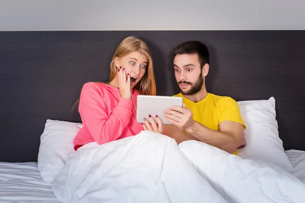 Joven dulce pareja en la cama viendo algo en la tableta Gadget — Foto de Stock