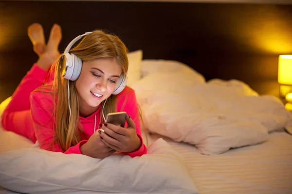 Νεαρές γυναίκες που ακούτε τη μουσική από το smartphone στο κρεβάτι — Φωτογραφία Αρχείου