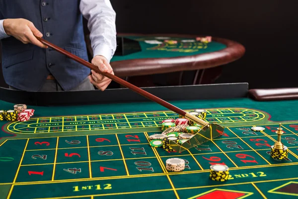 Croupier verzamelt chips met behulp van de stick in casino. — Stockfoto