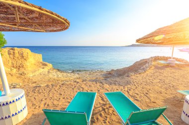 Güneş şemsiyeleri ve boş şezlonglar sahilde kum plaj