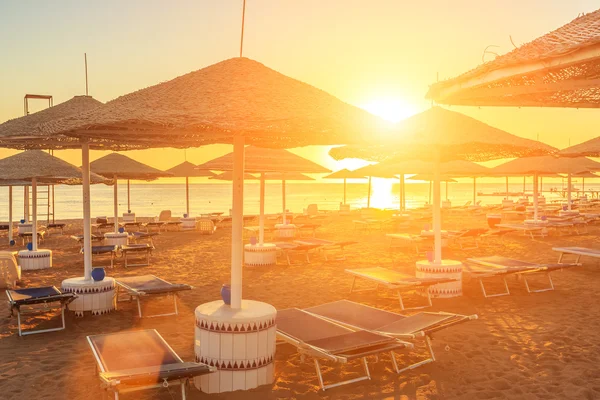 Strand med solstolar och parasoll under vacker soluppgång — Stockfoto