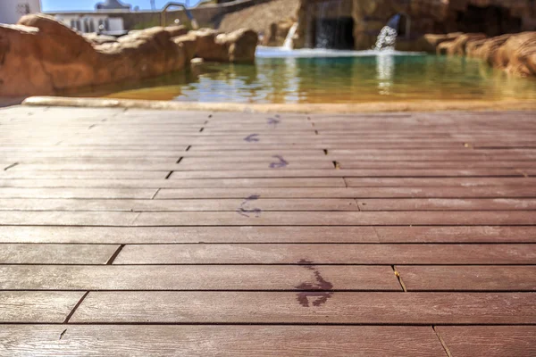 Pegadas de close-up no chão de madeira atrás dela piscina — Fotografia de Stock