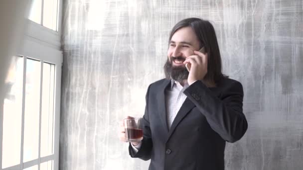 Jonge man dragen pak praten op een mobiele telefoon in de ochtend op een venster met kopie ruimte, — Stockvideo