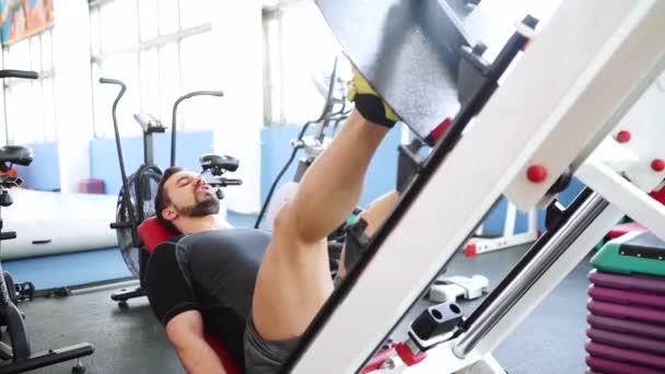 Attraktiver junger Mann macht Beinpresse an Maschine in Turnhalle — Stockvideo