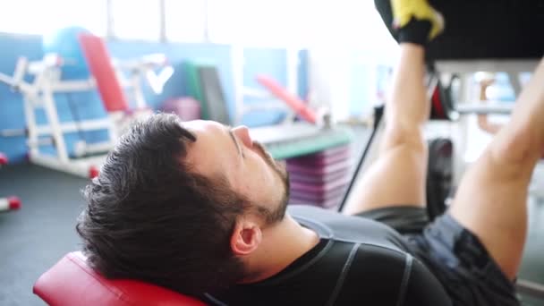 在健身房里，有魅力的年轻人在机器上按腿 — 图库视频影像