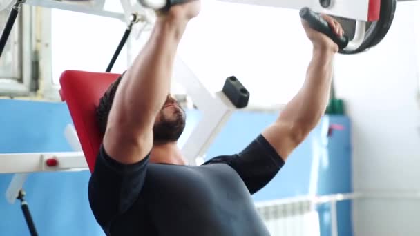 Hombre ejercitando los músculos de su brazo levantando dos pesas sin pesas en un club de fitness . — Vídeos de Stock