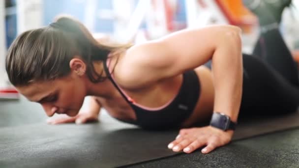 Mujer joven atlética haciendo flexiones. Vista frontal de cerca del reloj inteligente — Vídeos de Stock