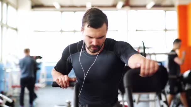 Uomo sorridente in bicicletta con orologio intelligente in palestra — Video Stock