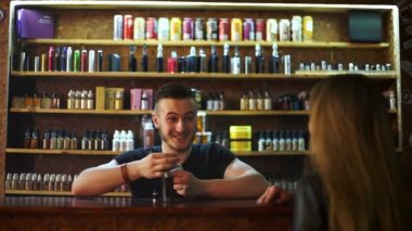 Vape shop 'taki satıcı genç kızlara e-sigara gösteriyor ve nasıl çalıştığını gösteriyor.