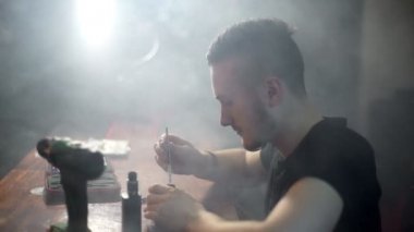 genç adam olun BKİ dumanlı vape dükkan inşa bir bobin