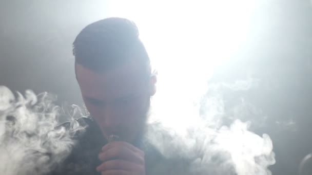 Unga vaper man andas ut stora moln av rök med e-cigarett vape i slowmotion — Stockvideo