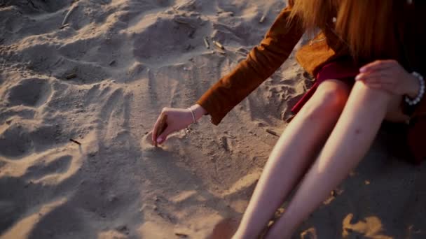 Bellezza ragazza disegna un cuore sulla sabbia sul tramonto spiaggia — Video Stock