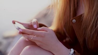 Kırmızı elbise sms manifatura app akıllı telefon plaj gün batımında kullanarak kadında Smartphone.