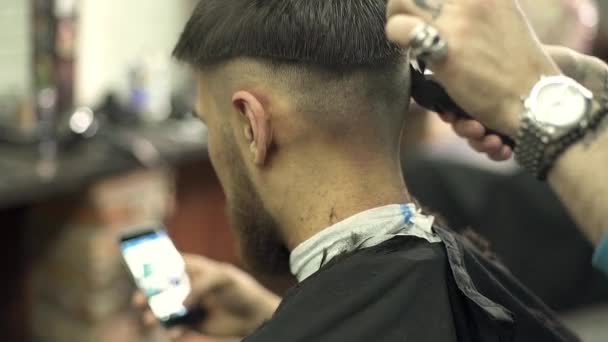 Jovem usando um telefone inteligente na barbearia — Vídeo de Stock