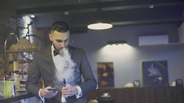 Bebaarde man met e-sigaret in interieur vapes — Stockvideo