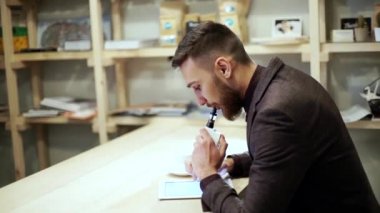 işadamı tablet ile bir e-sigara vape okuma takım elbiseli
