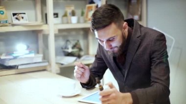 Kameraya bakarak bir e-sigara vape ile gülümseyen iş adamı tablet üzerinde okuma takım elbiseli