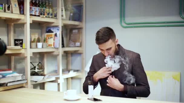 Barbudo hombre de traje está fumando vapor de cigarrillo electrónico, y recto su corbata — Vídeo de stock