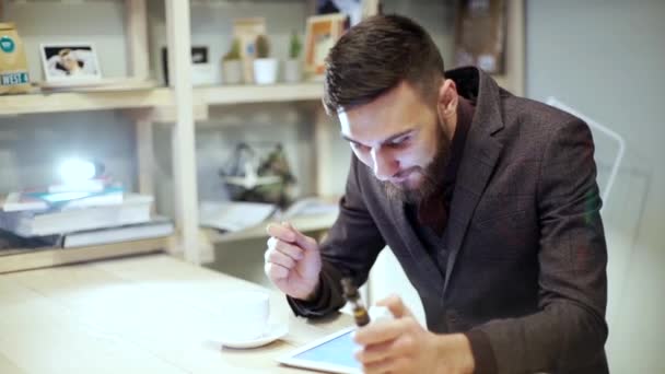 homme d'affaires dans un costume de lecture sur tablette, souriant avec un e-cigarette vape regardant la caméra 