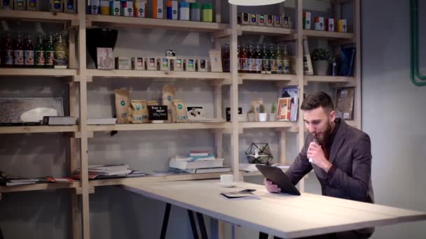 Moderno uomo d'affari hipster che beve caffè nel caffèe lavora sul vaporizzatore di sigarette elettroniche per tablet — Video Stock