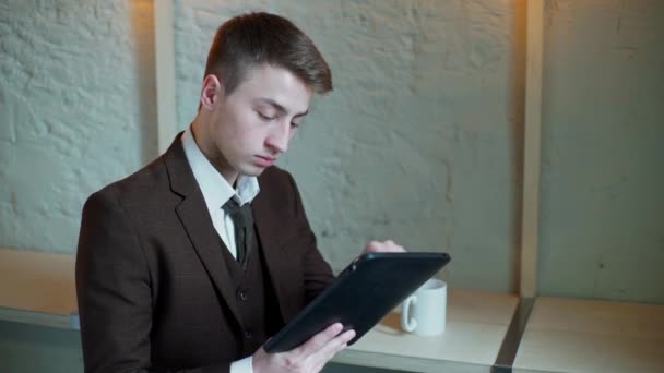 Hombre de negocios serio que trabaja en la computadora de la tableta en el café y mirando a la cámara — Vídeos de Stock