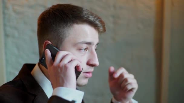 Счастливый молодой бизнесмен разговаривает по мобильному телефону в кафе — стоковое видео