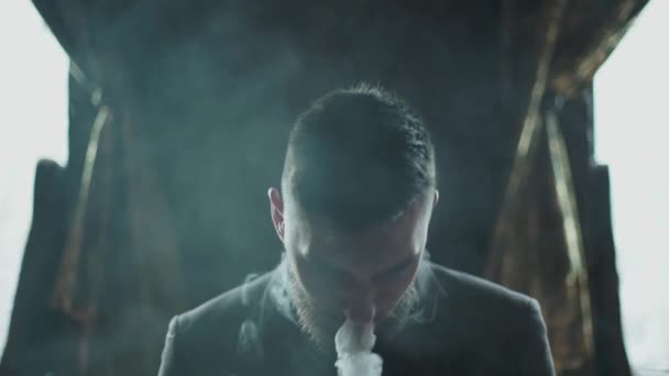 Närbild av en skäggig man i kostym röka elektronisk cigarett — Stockvideo