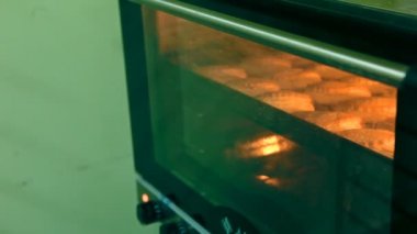 Bir fırıncı çörekler bir tepsi fırından çekiyor