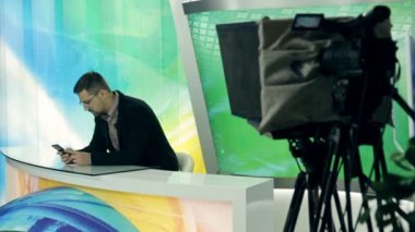 Bir haber sunucusu reklam sırasında telefona bakıyor