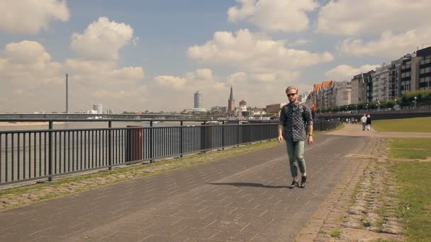 Hipster tourist is walking along European embankment. — Stock Video