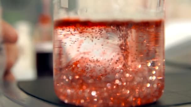 Está fluyendo material rojo líquido con partículas brillantes — Vídeos de Stock