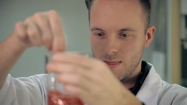 De laboratorian is de ingrediënten in een glas mengen. — Stockvideo