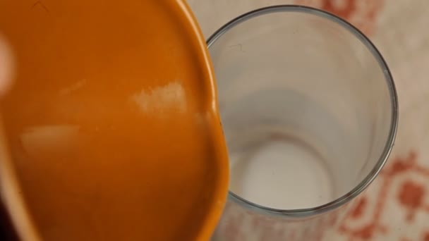 Melk in een glas van een kruik gieten — Stockvideo