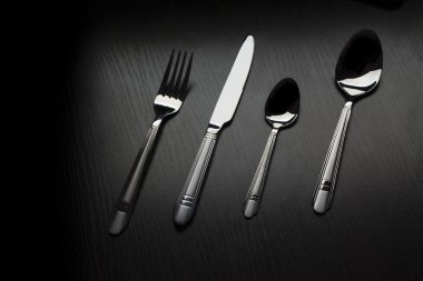 siyah bir masada çatal bıçak takımı