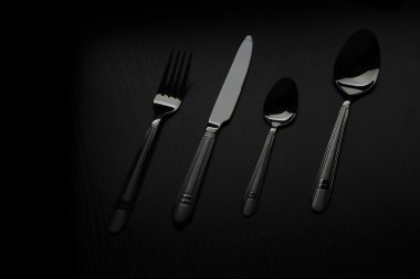 siyah bir masada çatal bıçak takımı