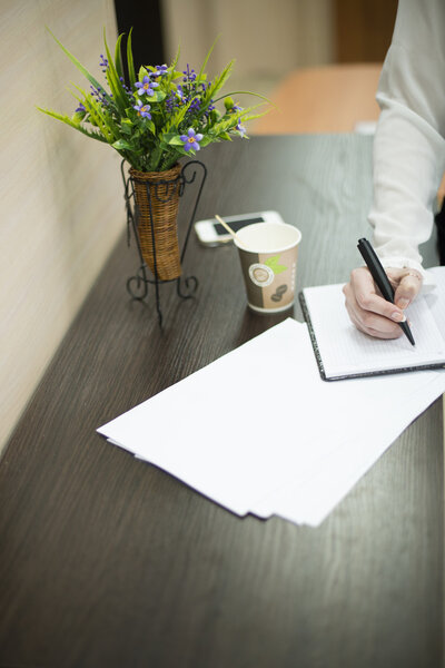 она пишет ручкой на блокноте
