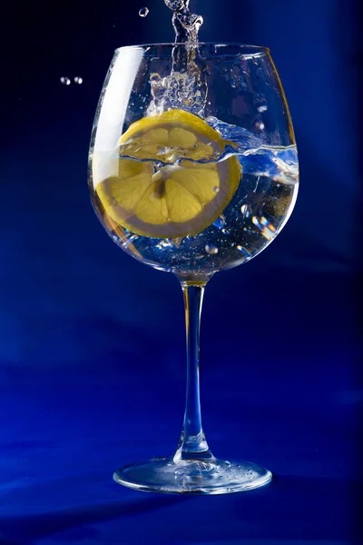 Rodaja de limón tirada en un vaso de agua Imágenes de stock libres de derechos